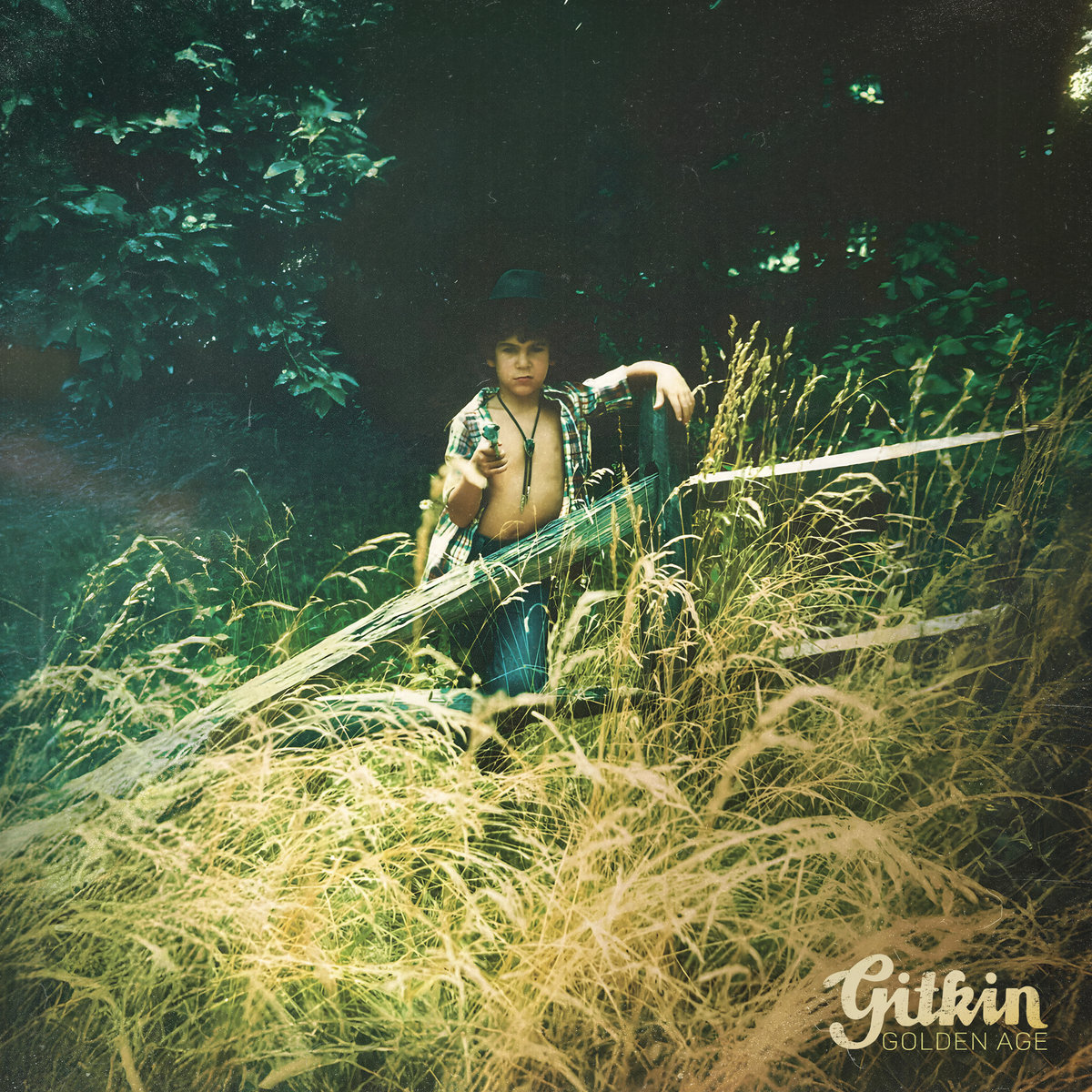 A person wearing an open button-down shirt standing among tall, dry, yellow grasses.