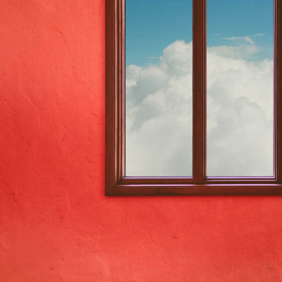 Clouds and a Blue Sky Seen Through A Window On A Red-Orange Wall
